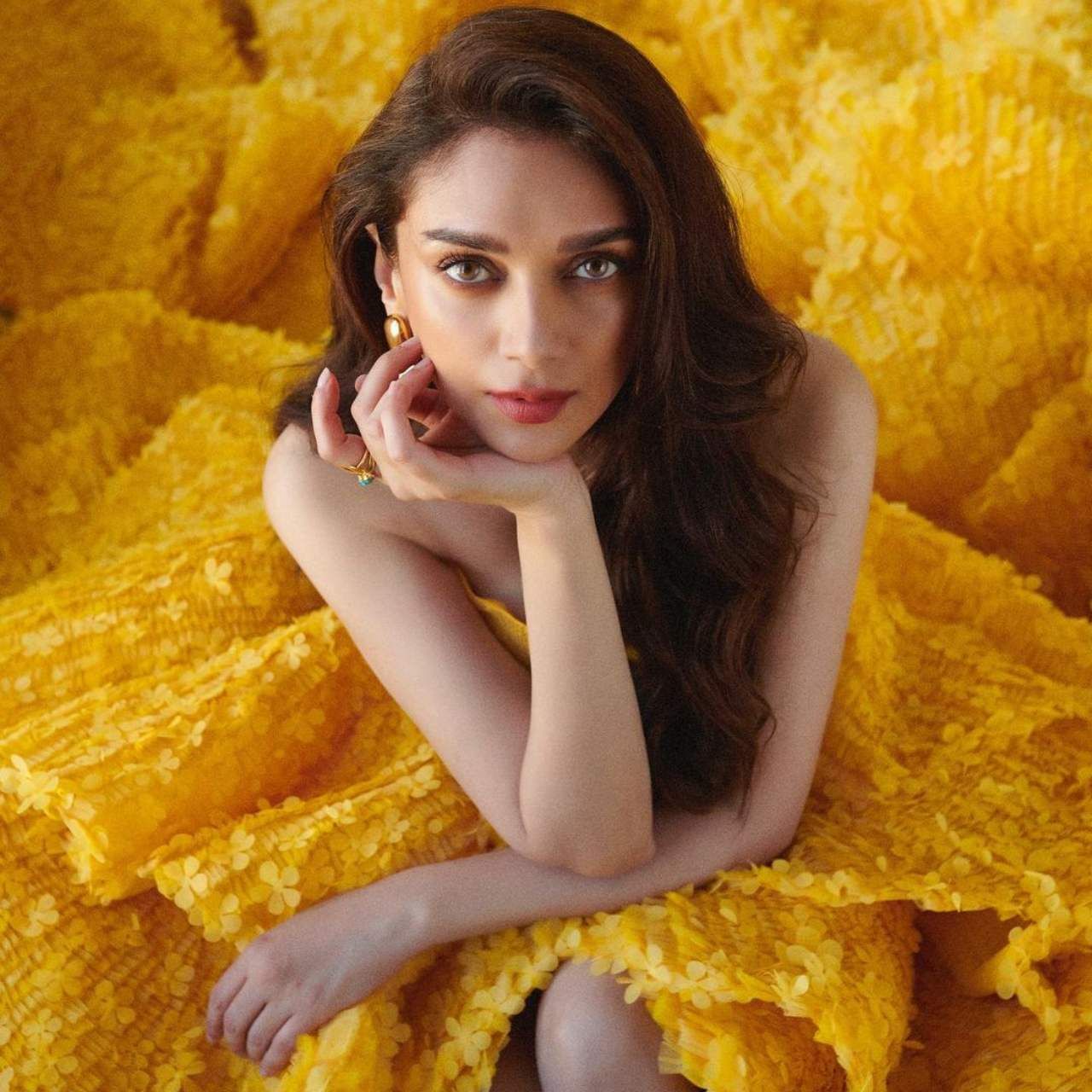 Aditi Rao Hydari is wearing a yellow gown in this picture.  This is gown off shoulder.  The actress is looking no less than Cinderella in this gown.  Layered design gown with matching gold earrings and ring wear.